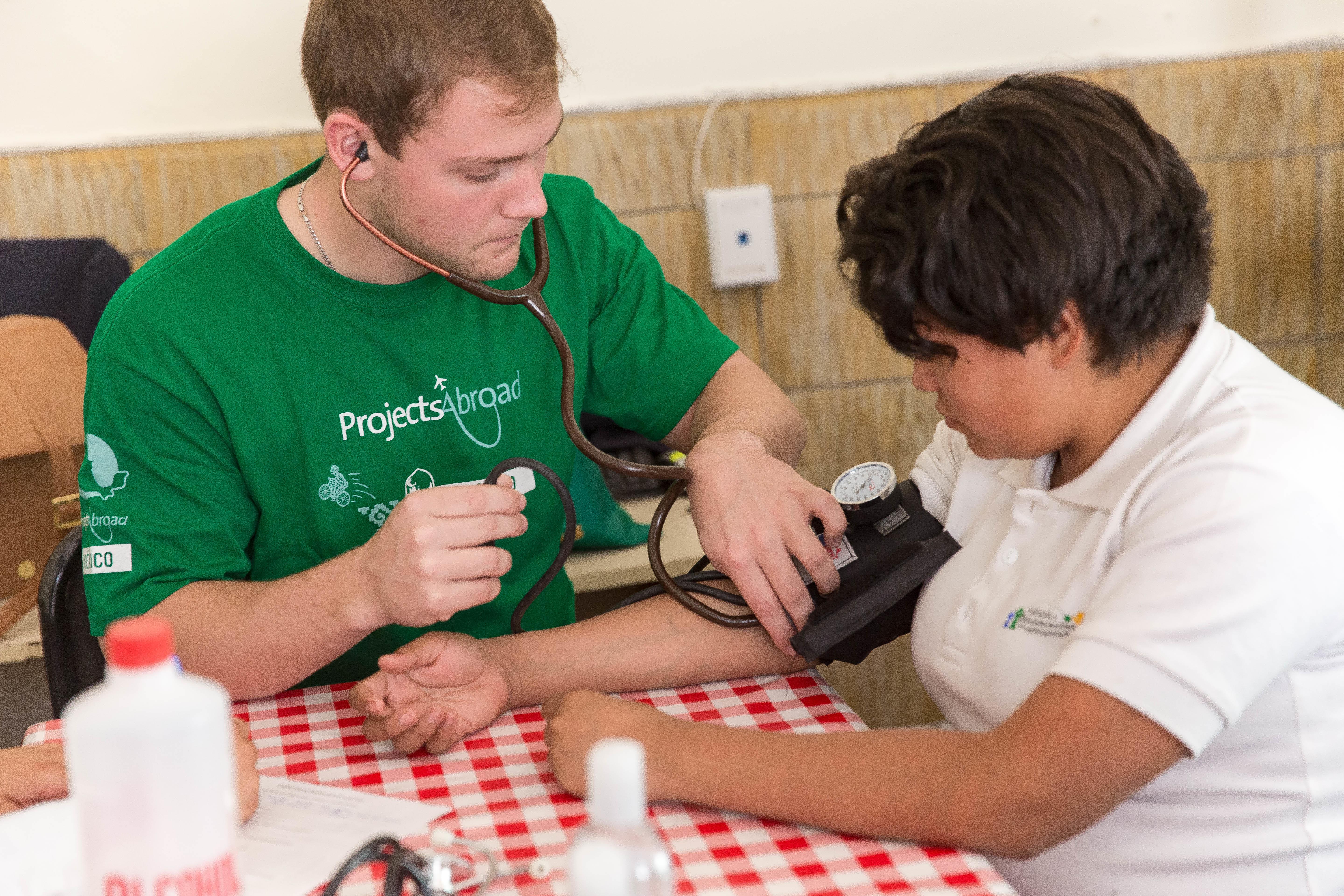 During a medical outreach an intern from Projects Abroad is checking the blood pressure of a patient as part of his nursing internship in Mexico. A male Projects Abroad intern is pictured taking the blood pressure of a local patient as part of his nursing internship in Mexico.